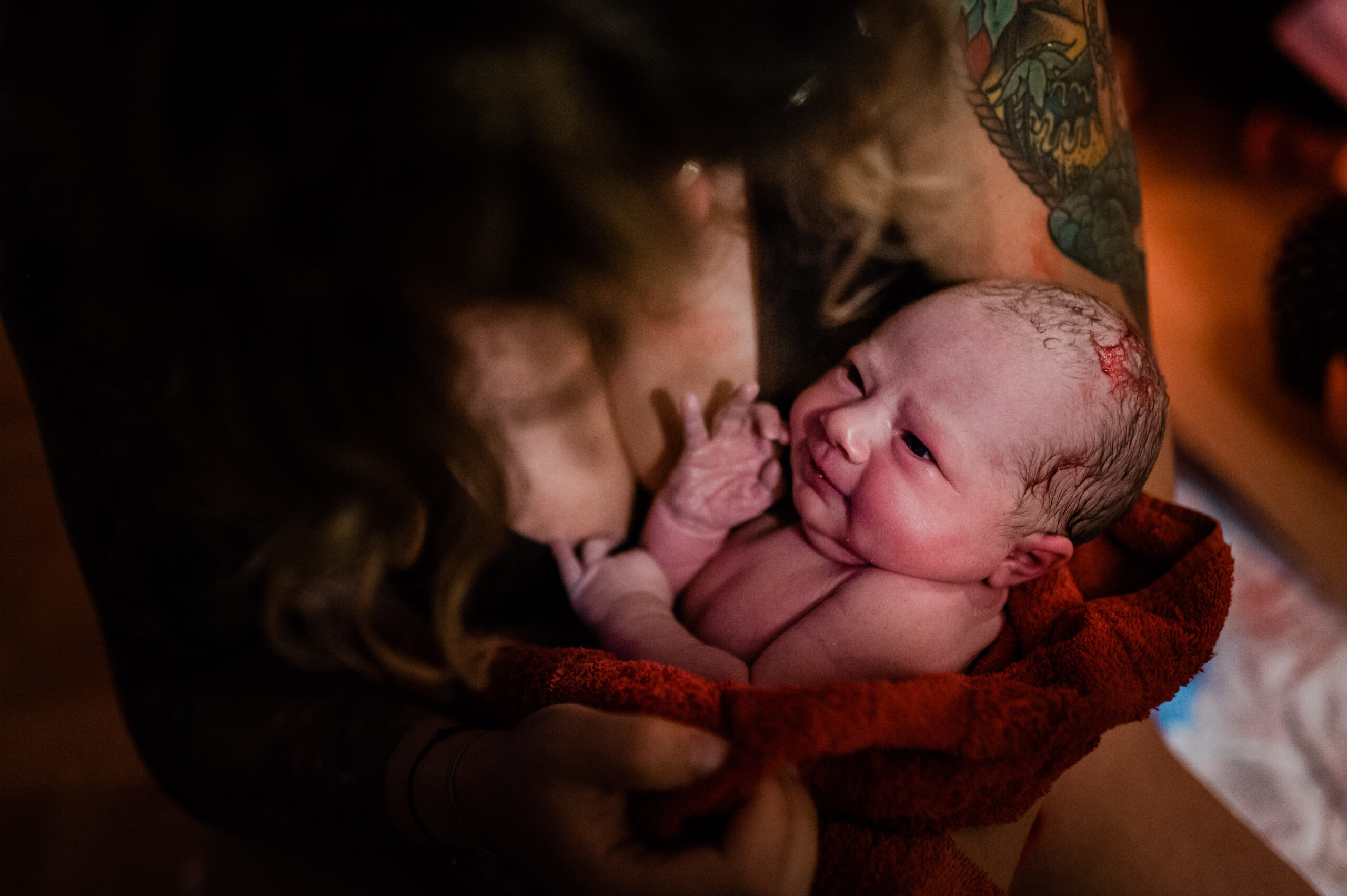 Ein Baby direkt nach der Geburt, im Arm der Mutter.