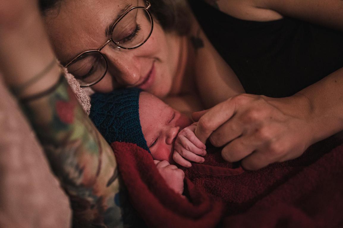 Eine Mutter kuschelt mit ihrem frischgeborenen Kind.