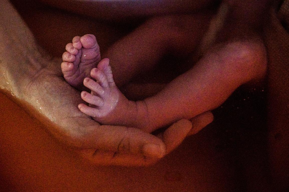 Eine Mutter hält die kleinen Füße ihres Babys in der Hand.