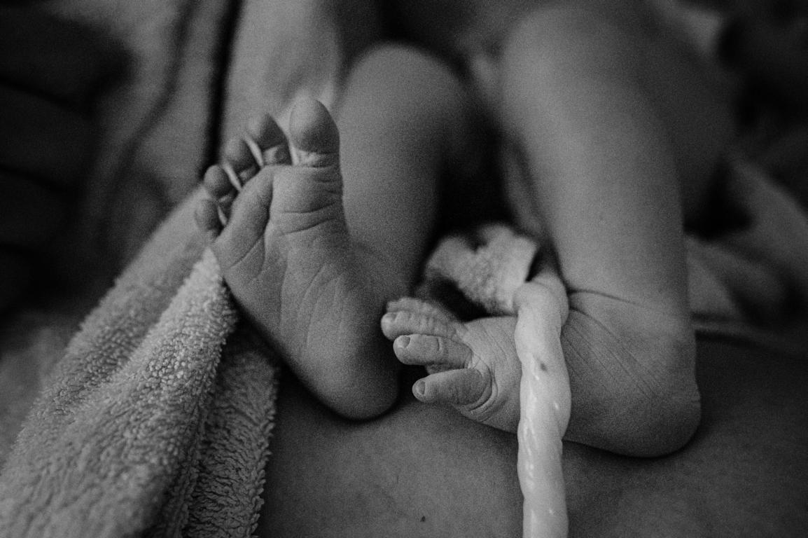 Schwarz-Weiß-Bild der kleinen Babyfüße und der Nabelschnur.