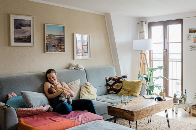 Eine Mutter stillt ihr Baby auf der Couch.